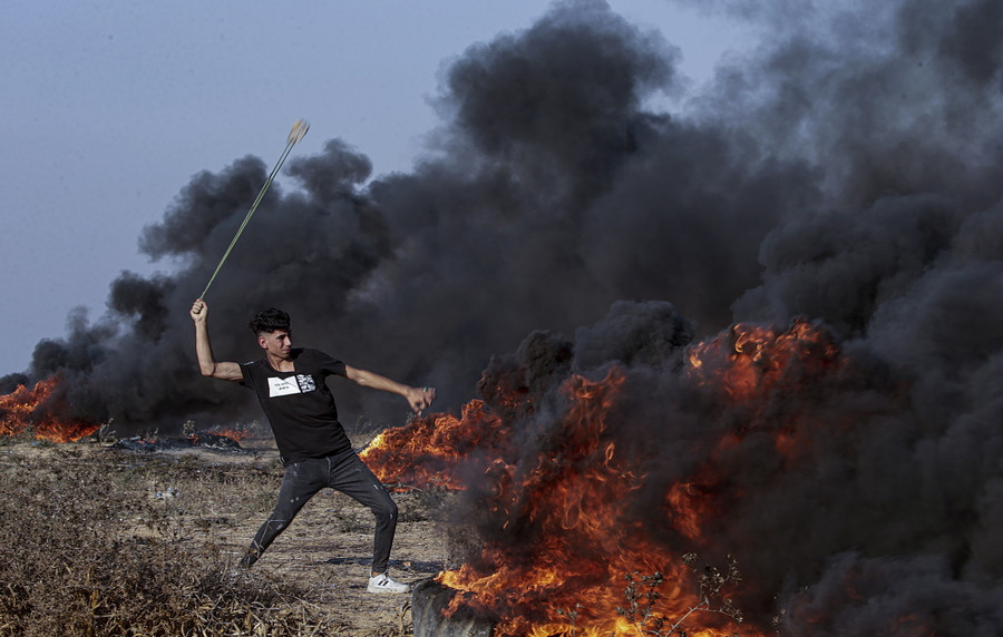 Παλαιστίνη / Παλαιστίνιος διαδηλωτής πετάει πέτρες στα ισραηλινά στρατεύματα στα σύνορα της Λωρίδας της Γάζας. EPA/MOHAMMED SABER