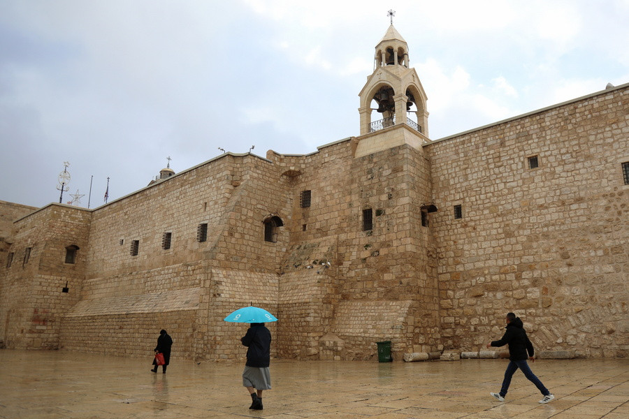 Επισκέπτες περπατούν κοντά στην εκκλησία της Γέννησης στην πόλη Βηθλεέμ της Δυτικής Όχθης. EPA/Wisam Hashlamoun