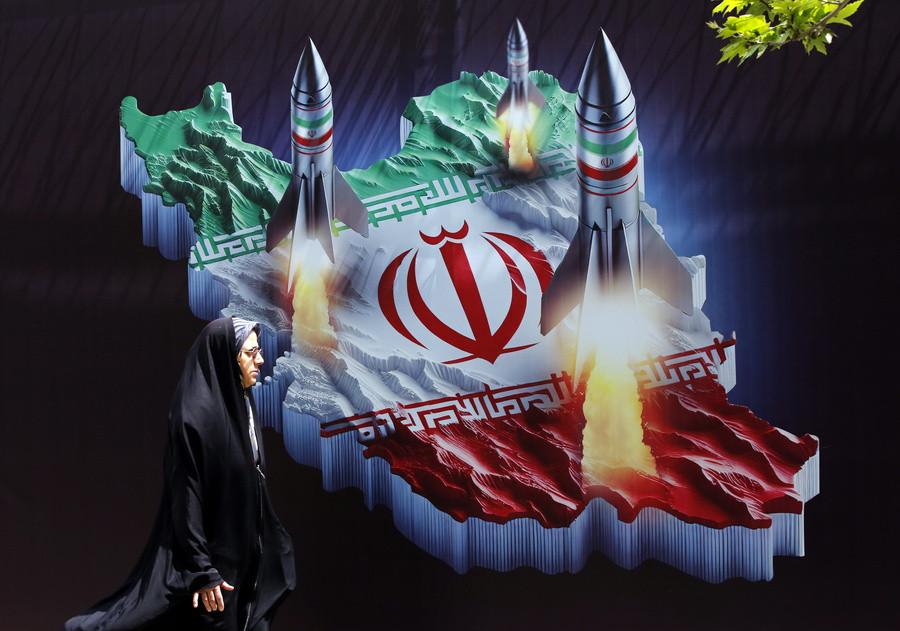 Ιρανή περπατά μπροστά από ένα πανό κατά του Ισραήλ που φέρει εικόνες ιρανικών πυραύλων, στην Τεχεράνη. EPA/ABEDIN TAHERKENAREH