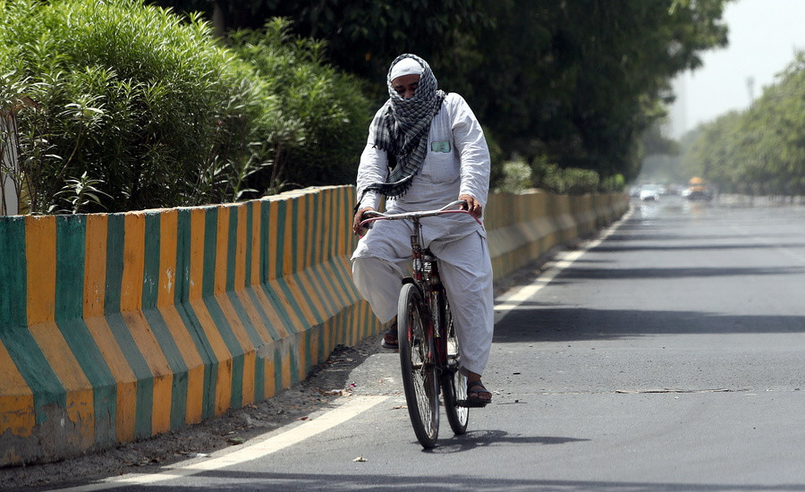 Ένας εργαζόμενος κάνει ποδήλατο ενώ καλύπτει το κεφάλι του με μια πετσέτα σε μια ζεστή μέρα στο Νέο Δελχί της Ινδίας, 29 Μαΐου 2024