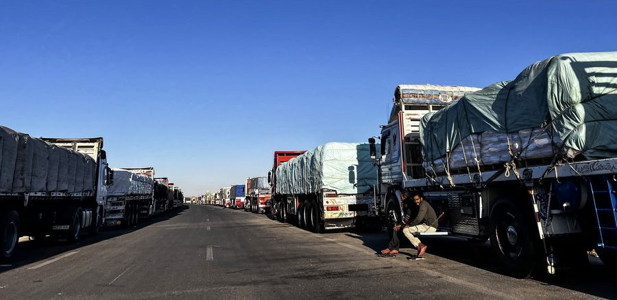 Φορτηγά που μεταφέρουν ανθρωπιστική βοήθεια για τη Γάζα παρατάσσονται περιμένοντας να κινηθούν προς το συνοριακό πέρασμα της Ράφα (EPA/STR)