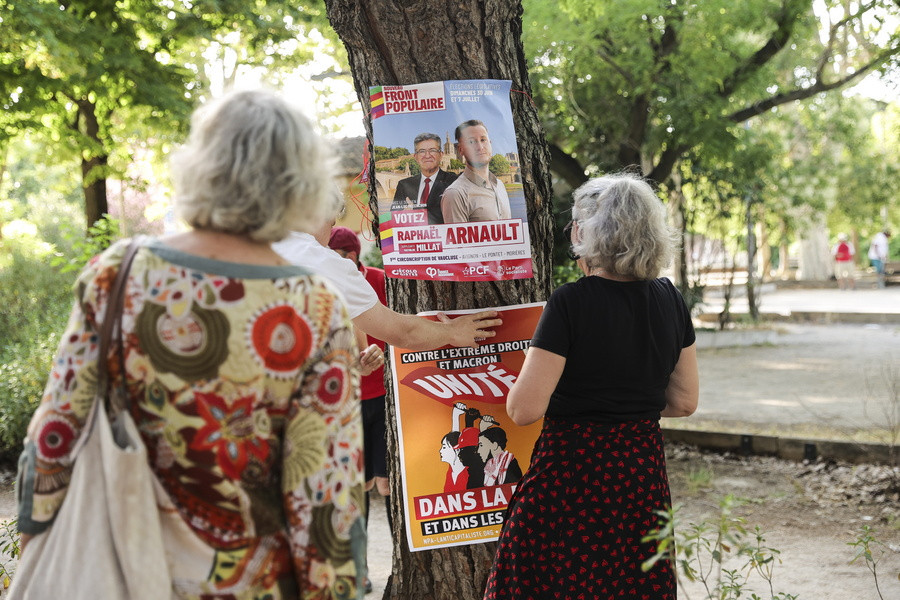 Γυναίκες κολλούν αφίσες με το πορτρέτο του υποψηφίου του Νέου Λαϊκού Μετώπου στην 1η εκλογική περιφέρεια της Vaucluse και εκπροσώπου της αντιφασιστικής ομάδας «La Jeune Garde» με έδρα τη Λυών, Raphael Arnault, κατά τη διάρκεια εκδήλωσης στην Αβινιόν (EPA/Teresa Suarez)
