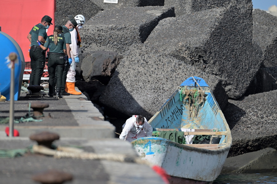 epa11611528 Some Spanish Civil Guard officers look at the boat that was intercepted off the Canary Islands coast with 57 migrants on board, at the port of La Restinga, El Hierro island, Canary Islands, southwestern Spain, 18 September 2024. Some 500 migrants, on board nine boats, were rescued by several Spanish Sea Rescue Unit's ships off the Canary Islands' coast on the night of 17 September.  EPA/Gelmert Finol