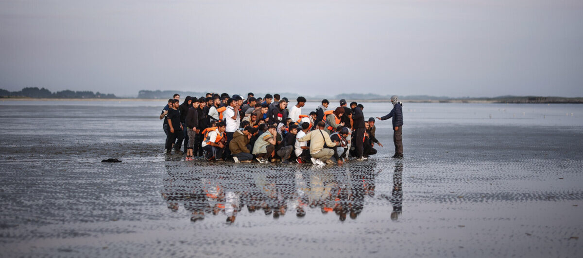 epa12569274 Migrants wait on a beach to board an inflatable dinghy boat to cross the English Channel, in Gravelines, northern France, 17 July 2025.  EPA/YOAN VALAT