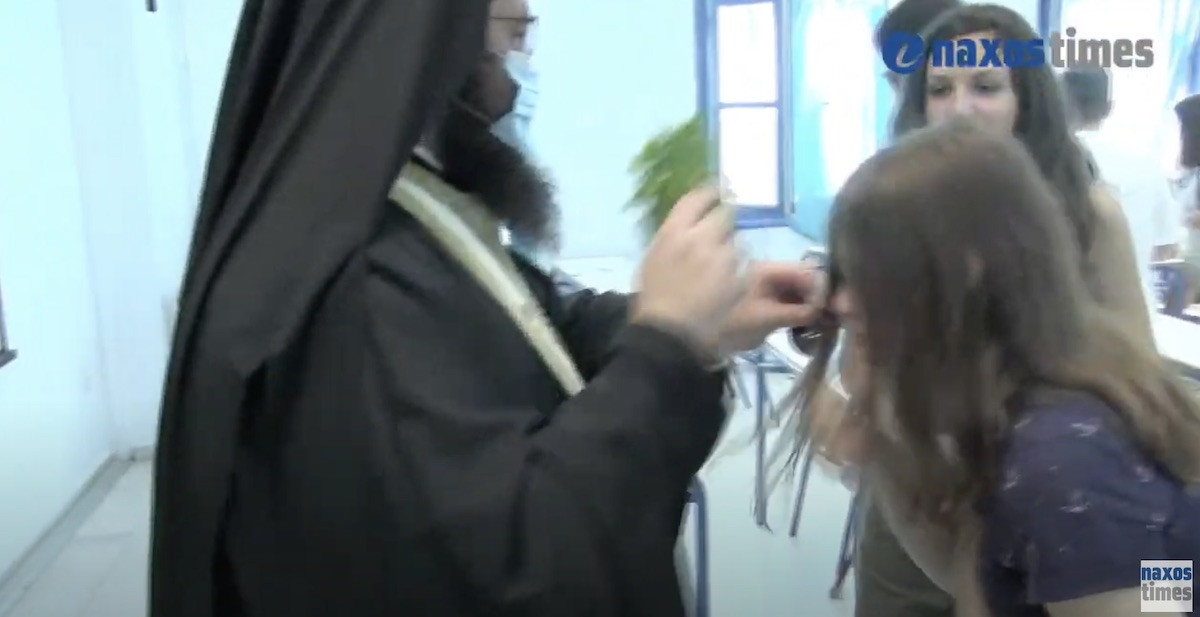 Ιερέας δίνει στους μαθητές να φιλήσουν το σταυρό χωρίς μάσκες